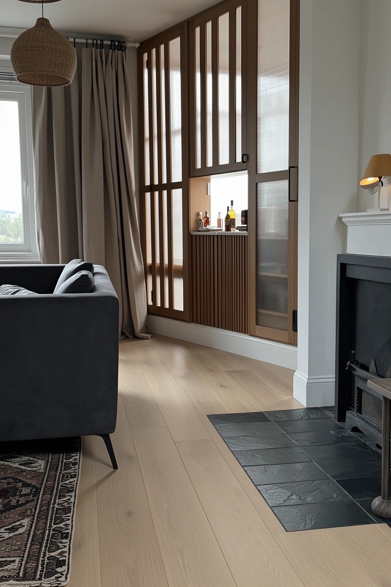 Living room corner with vertical slatted wood panels concealing a bar cabinet next to a dark gray sofa and fireplace