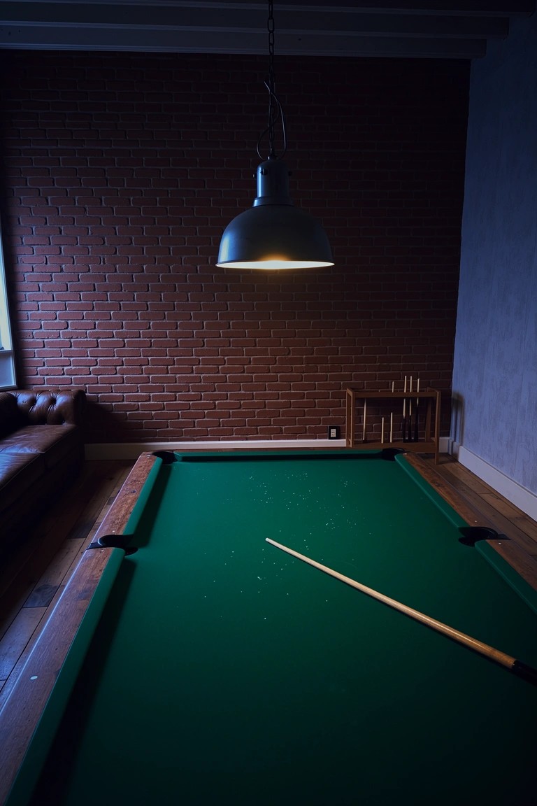 Green pool table in rustic man cave with brick wall, leather sofa, and overhead lamp
