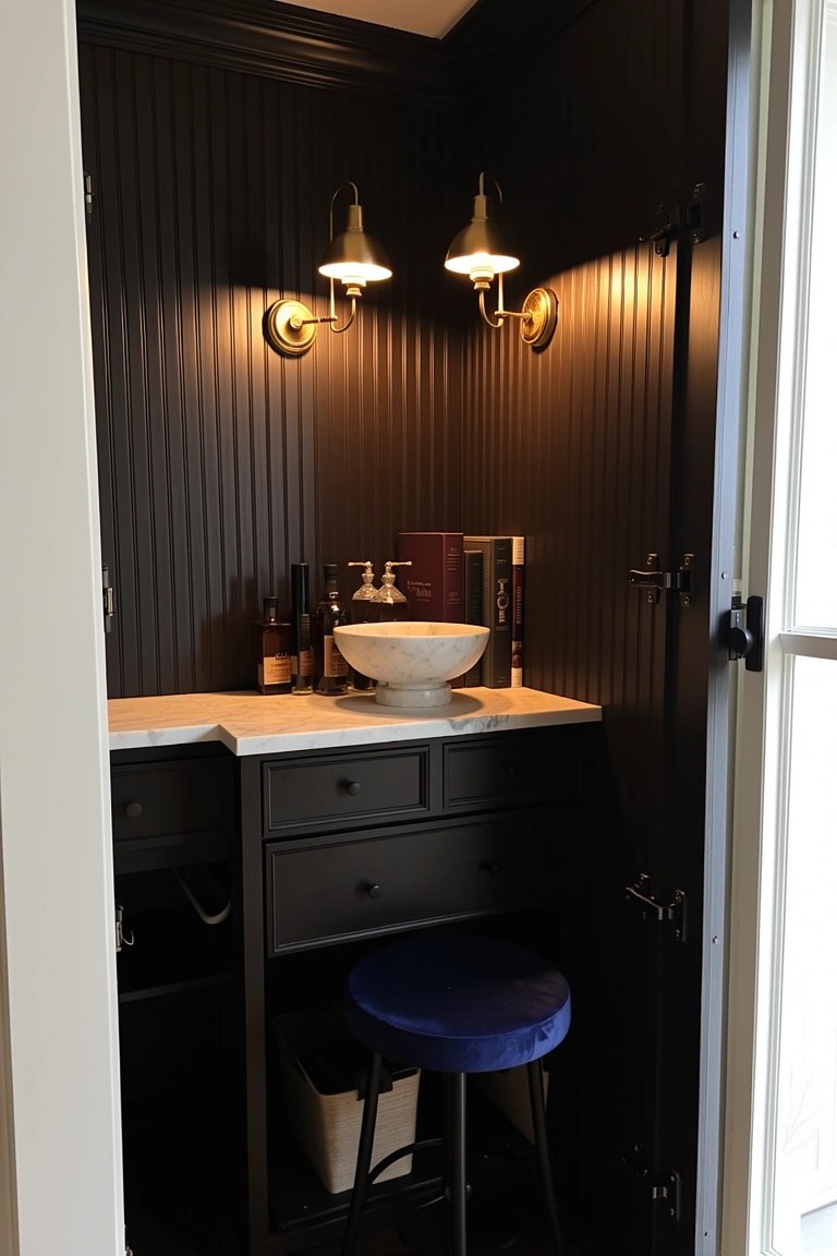 Dark-paneled corner nook with marble vanity, white bowl sink, liquor bottles, books, blue stool, and brass wall sconces