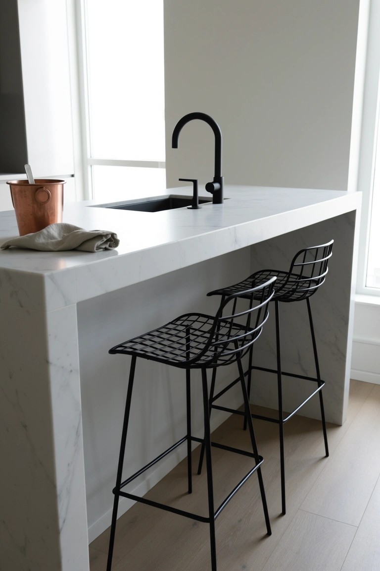 White marble kitchen island bar with black wire barstools, matte black faucet, and copper mug on counter