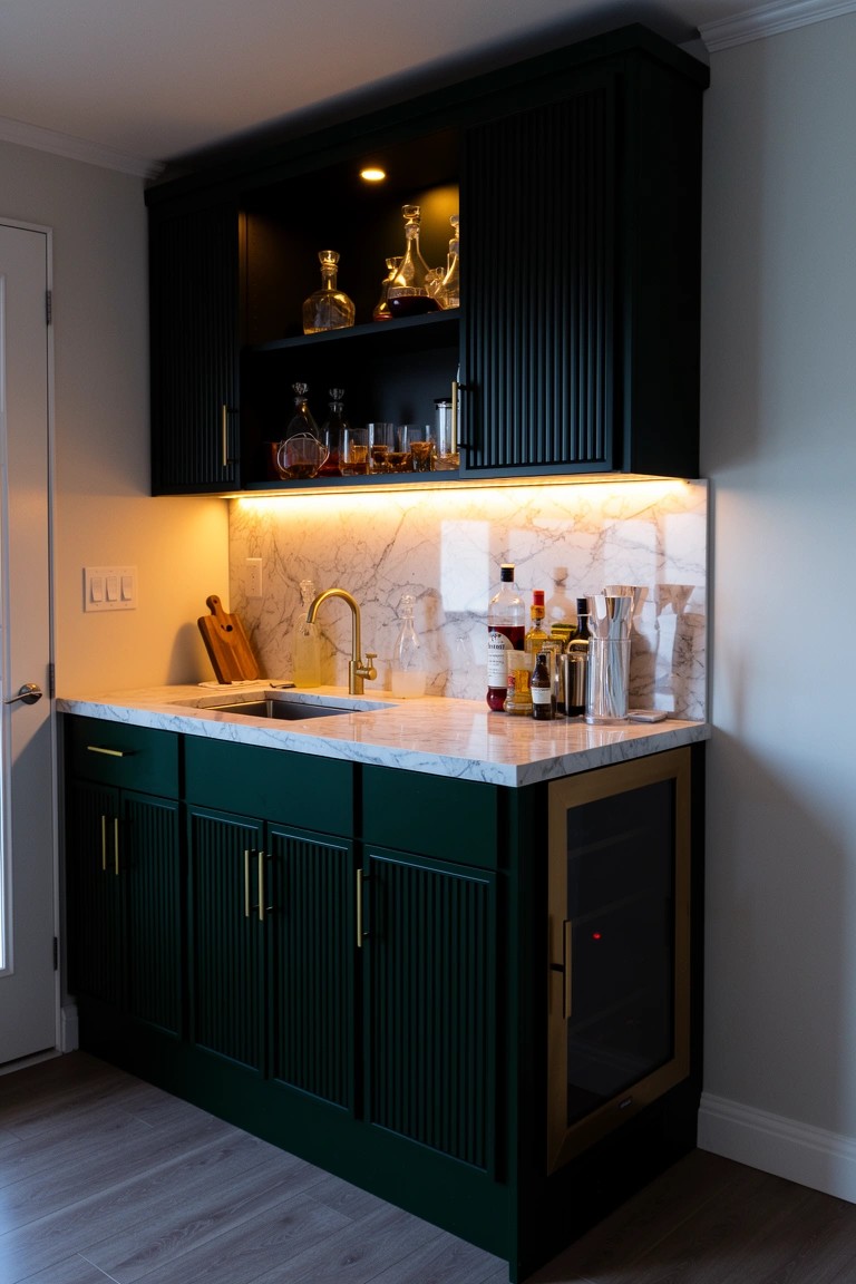 Compact built-in wet bar featuring dark green reeded cabinets, marble countertop with sink, LED backsplash, and liquor storage