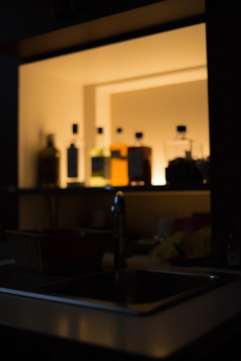 Kitchen sink with backlit shelves displaying glowing liquor bottles for a speakeasy vibe