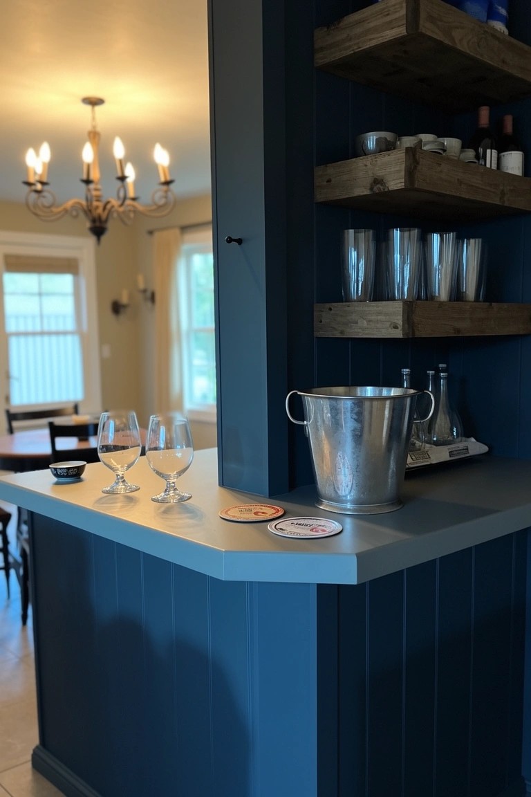 Navy blue paneled bar cabinets with wood shelves stocked with glasses and bottles, plus a silver ice bucket on the counter