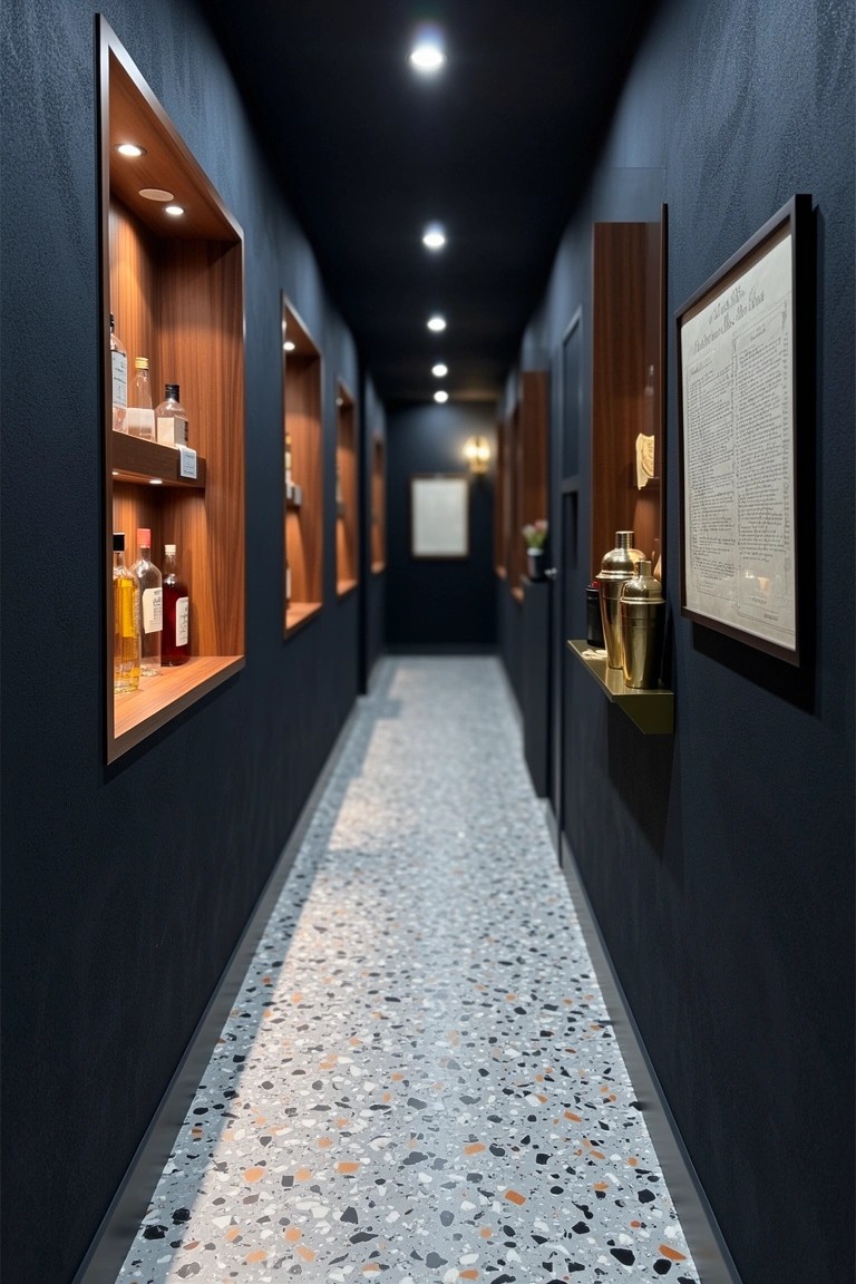 Narrow dark hallway with recessed wooden shelves displaying backlit liquor bottles and gold shakers along terrazzo floor