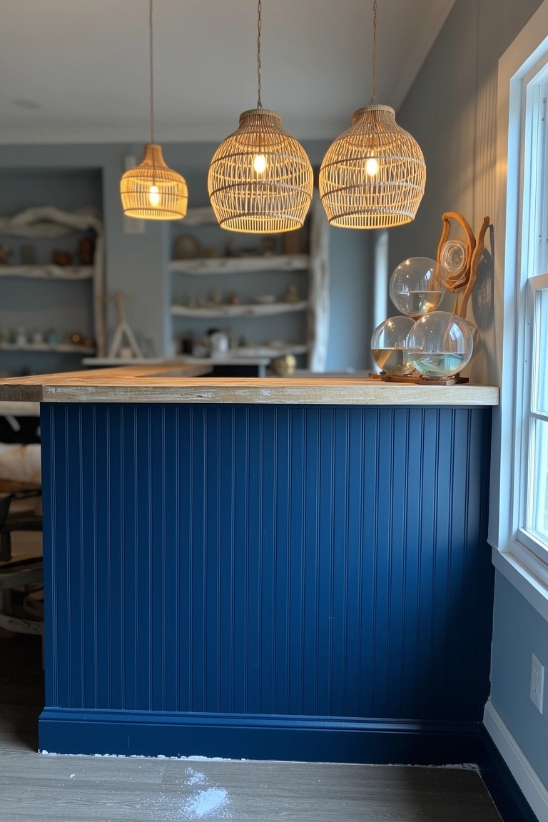 Navy blue vertical paneled bar island with butcher block top and rattan pendant lights hanging over it