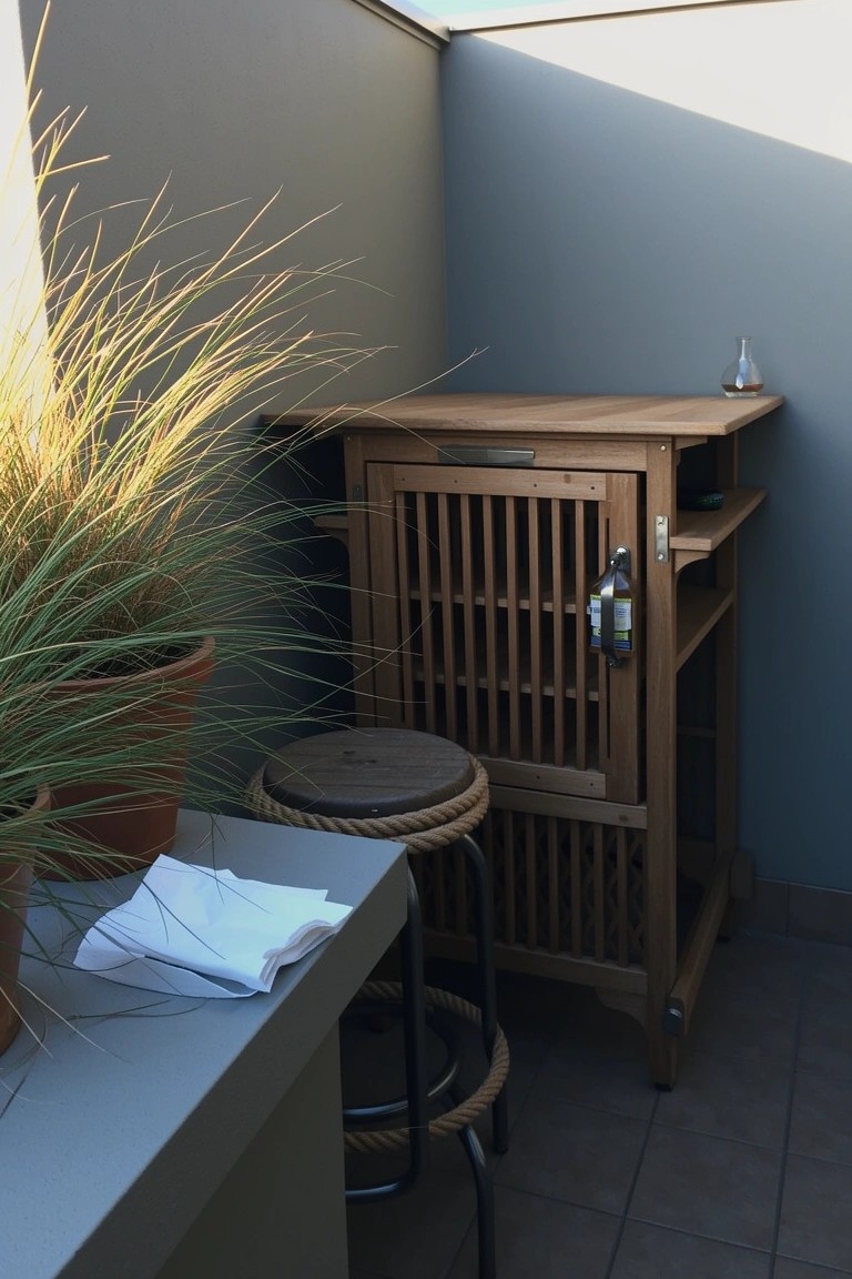 Tall wooden slatted cabinet used as bar station on balcony with stool and potted grass