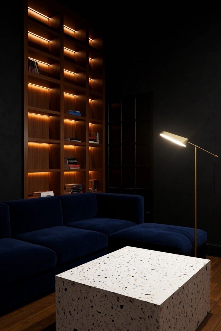 Dark living room with backlit wooden bookshelves on black wall, navy blue L-shaped sofa, white terrazzo coffee table, and gold floor lamp