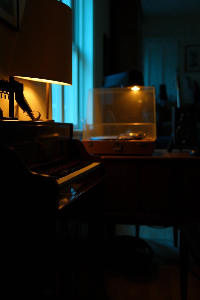 Cozy corner with black upright piano beside wooden record player under warm lamp glow