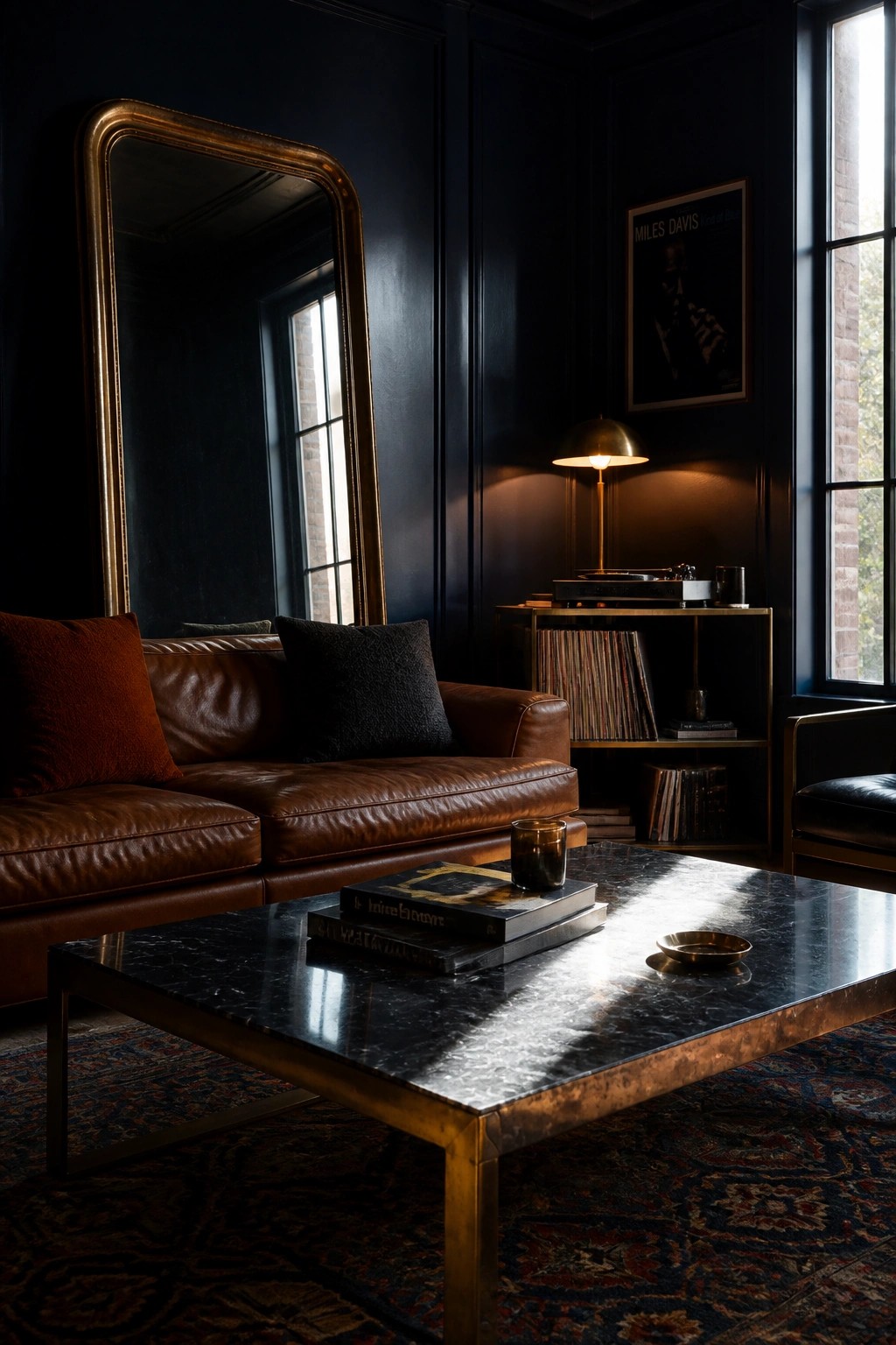 A masculine living room with dark navy walls, a brown leather sofa, a black marble coffee table, and a record console area.