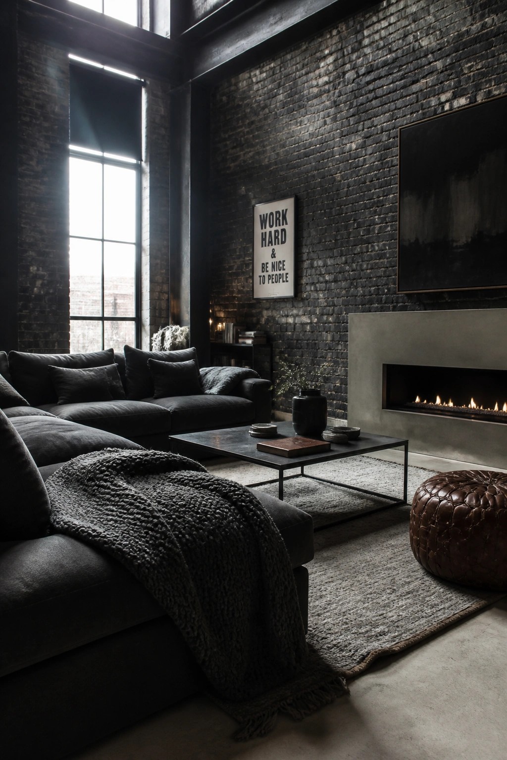 A dark masculine living room featuring black brick walls, a dark sectional sofa with a knit throw, a black coffee table, a modern linear fireplace, and a large abstract painting.