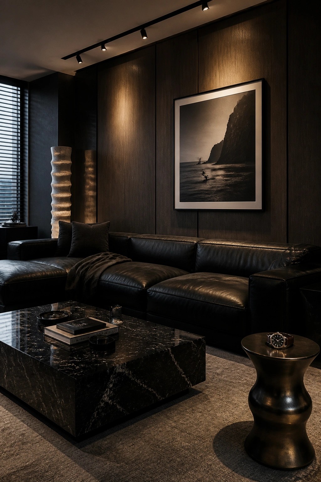 A living room with a large black leather sectional sofa, a black marble coffee table, dark wood walls, and a framed black and white photograph above the sofa.