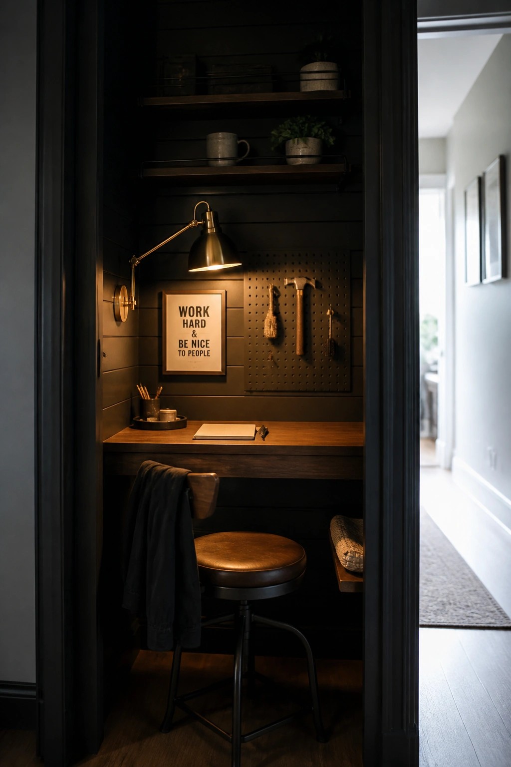 Dark wooden desk nook with leather stool, lit lamp, pegboard, and shelves