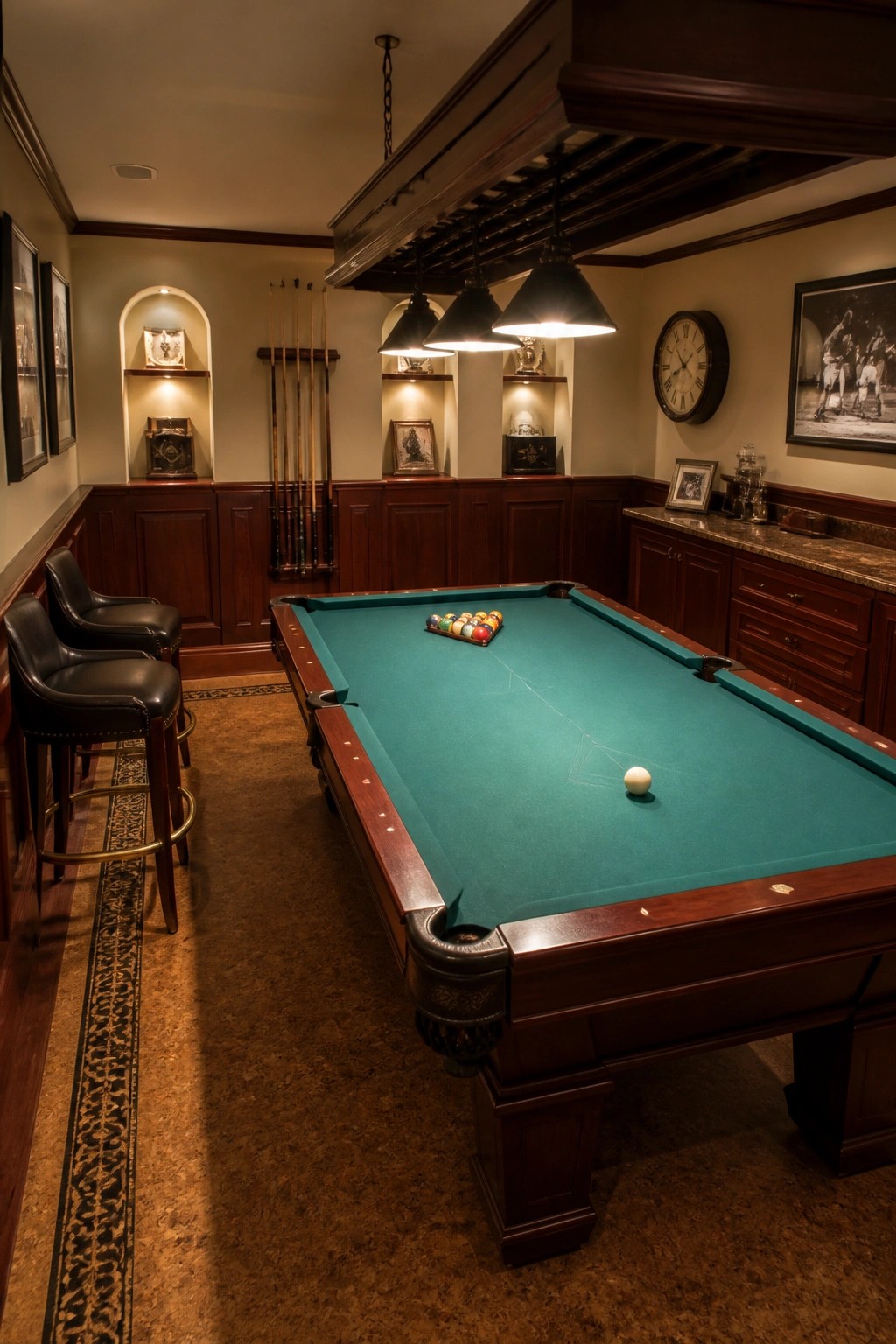 A billiards room featuring a green felt table, dark wood paneling with lit niches, and three pendant lights overhead.