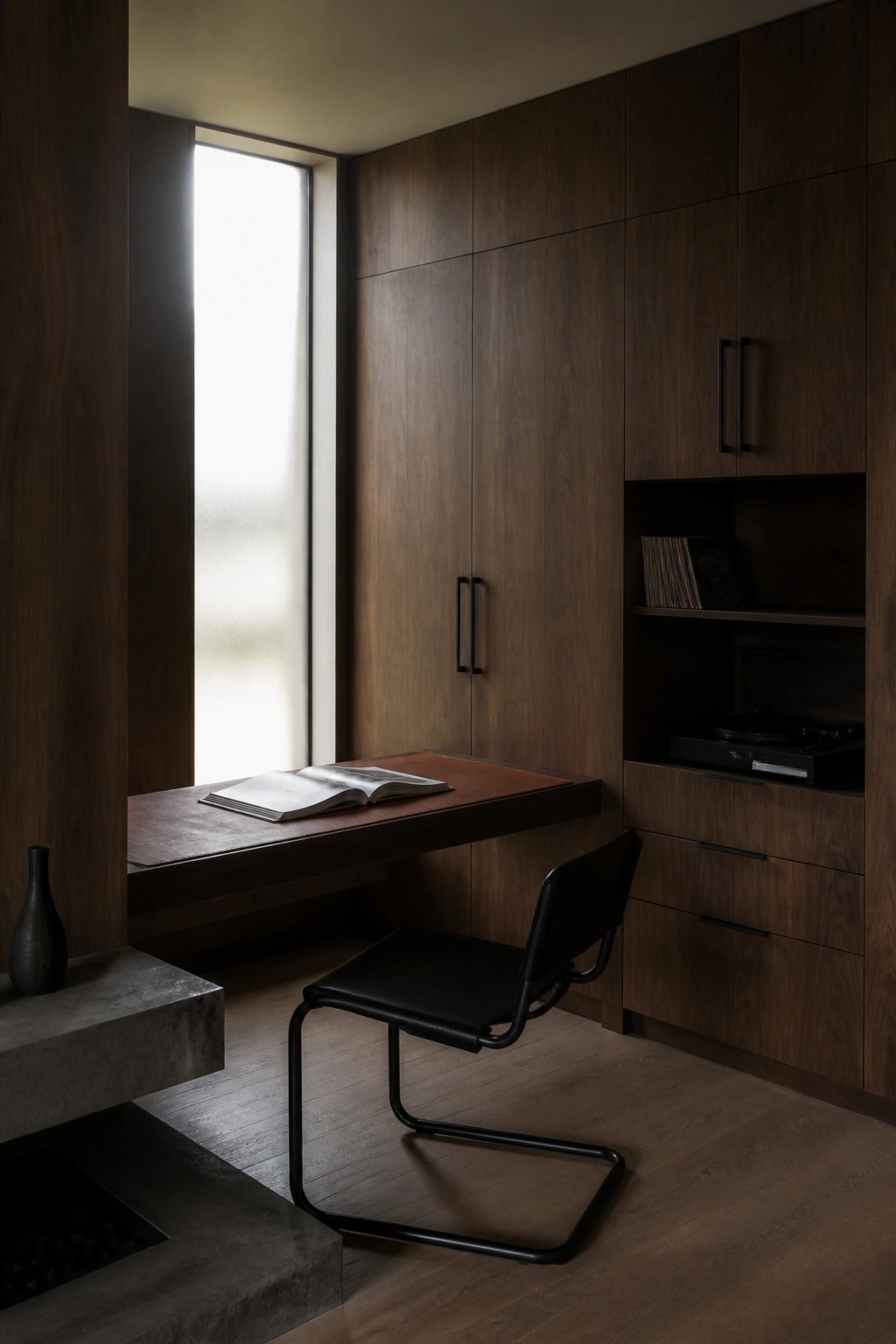 Minimalist dark wood study with floating desk, black chair, open book, and record player.
