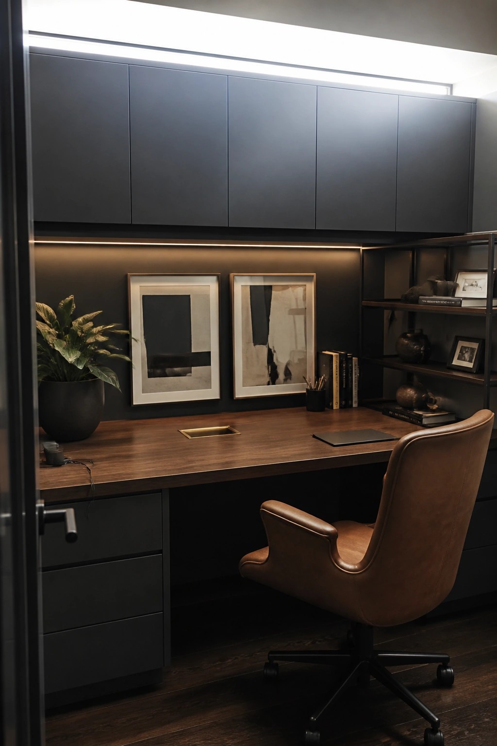 A home office with a wooden desk, dark built-in upper cabinets, a brown leather swivel chair, and two framed abstract prints on the wall.