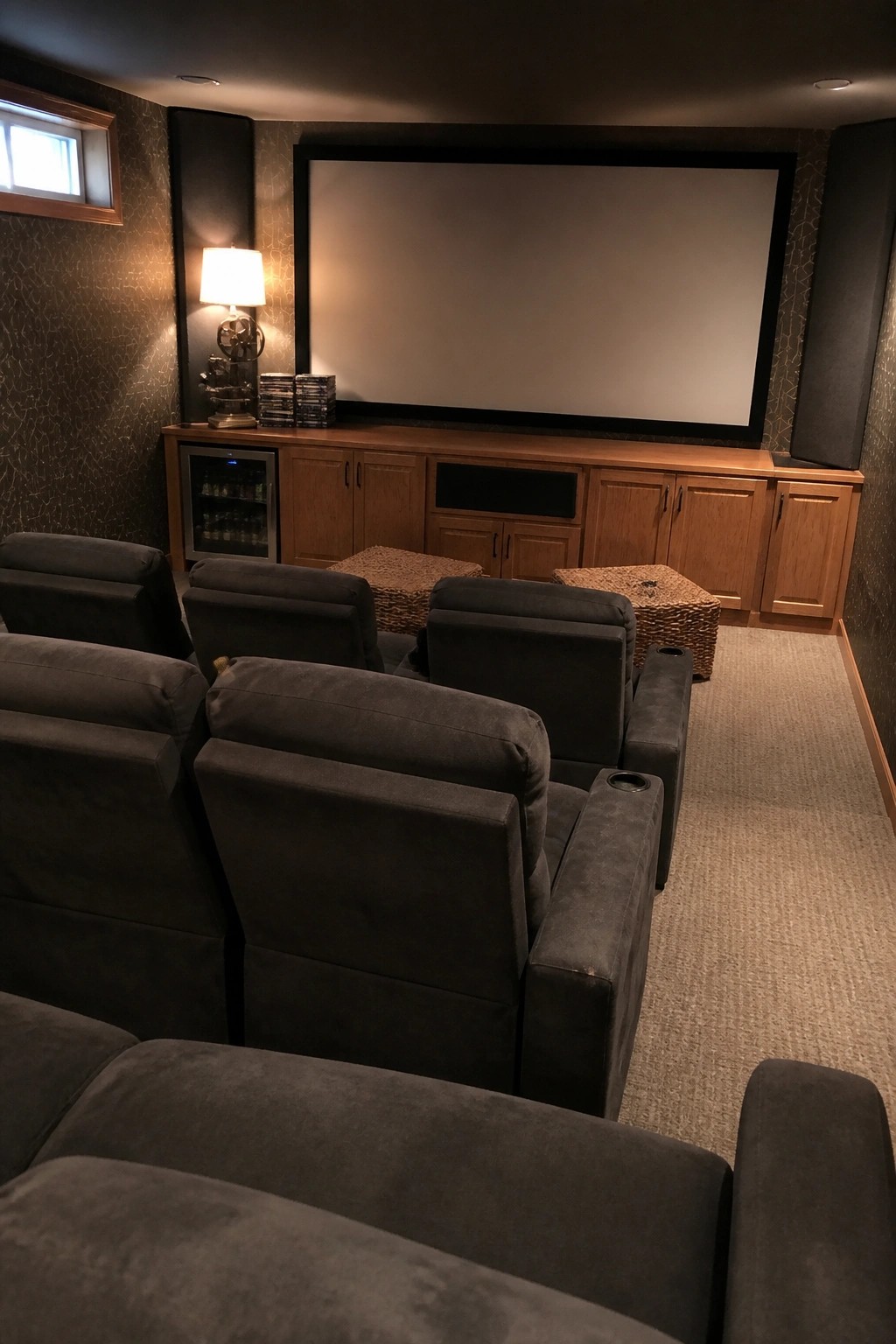 Dark gray recliners facing a large screen and wooden media console in home theater.