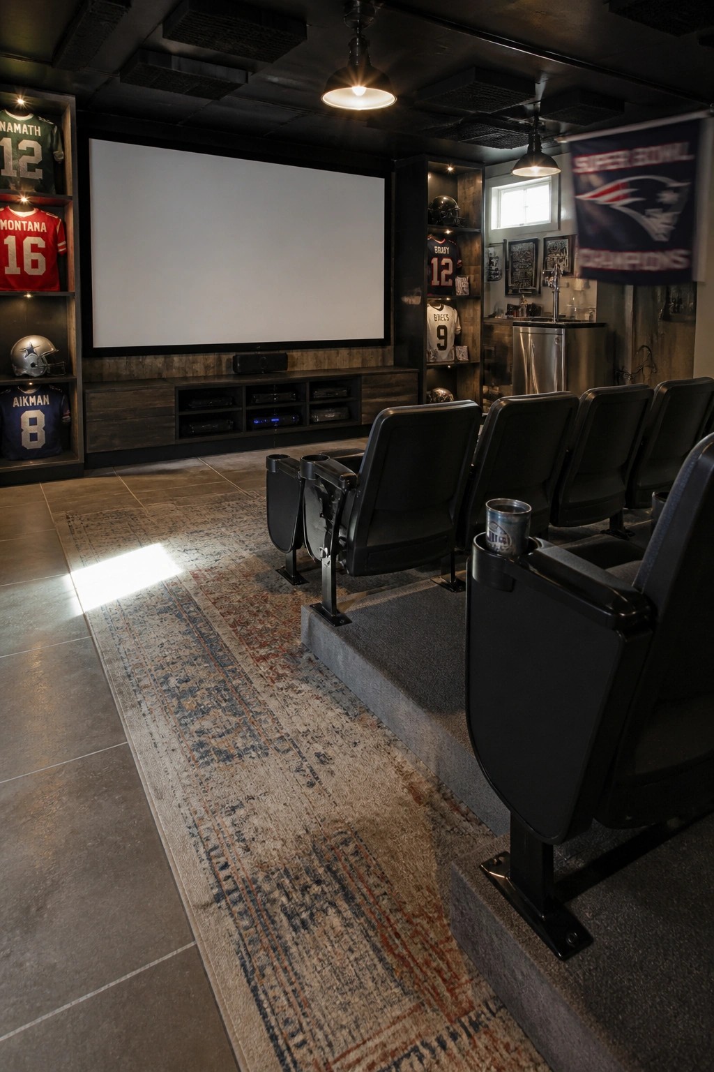 Home theater with black recliners, large screen, NFL jerseys, and Patriots banner.