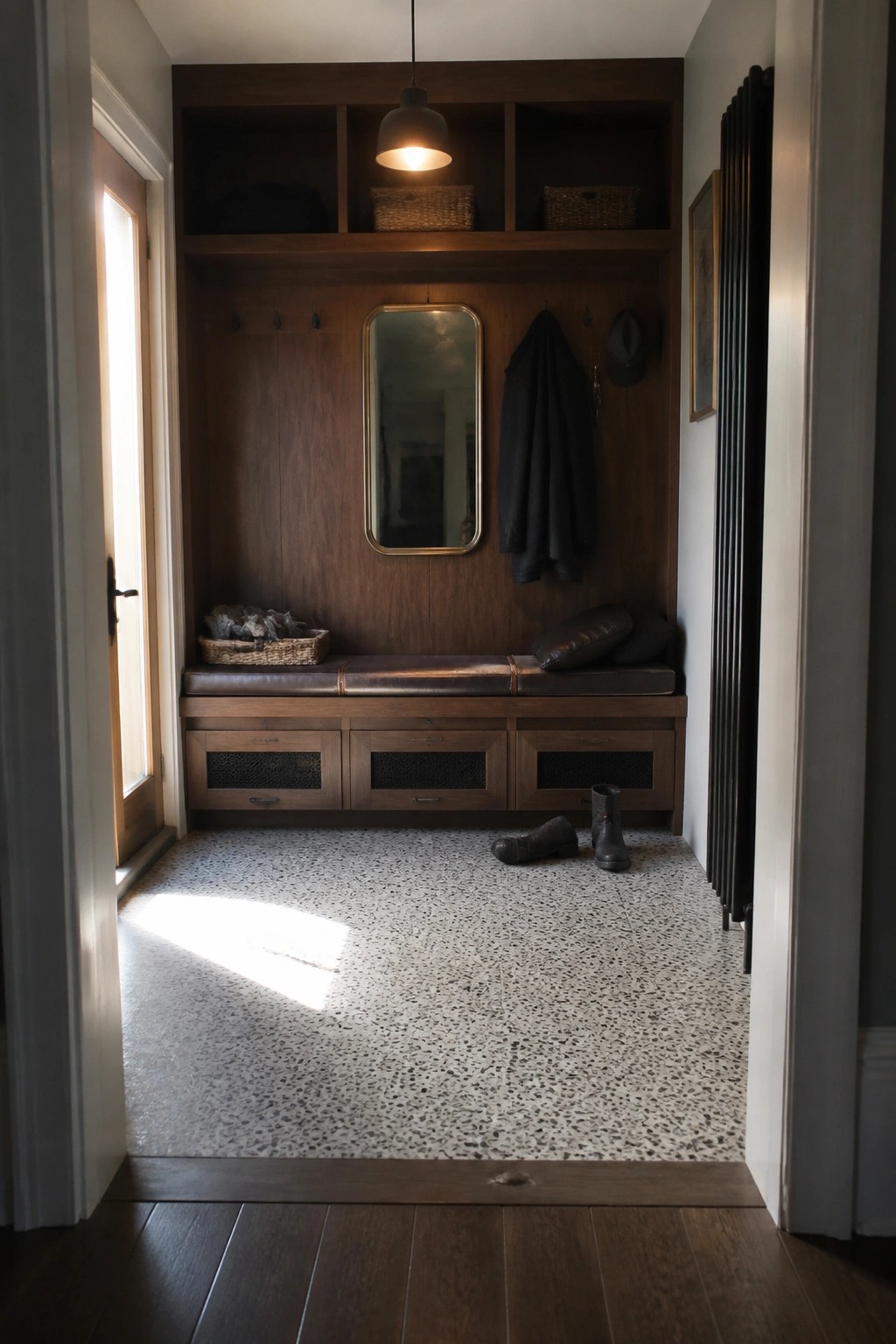 Wooden mudroom with cushioned bench, mirror, hanging coat, boots on terrazzo floor