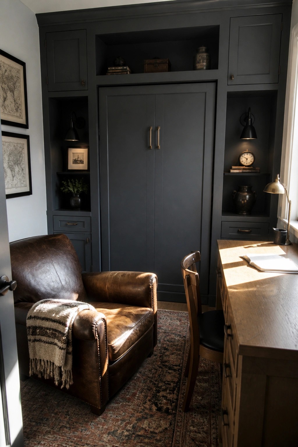 Dark built-in cabinetry with tall doors and side niches holding books, a clock, and vases, next to a brown leather chair and wooden desk in a home office.