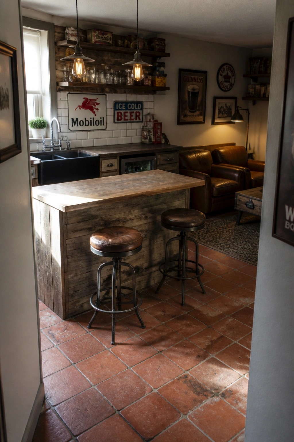 A rustic interior bar area with a reclaimed wood counter, two brown leather stools, vintage signs on a white tile wall, and terracotta floor tiles.