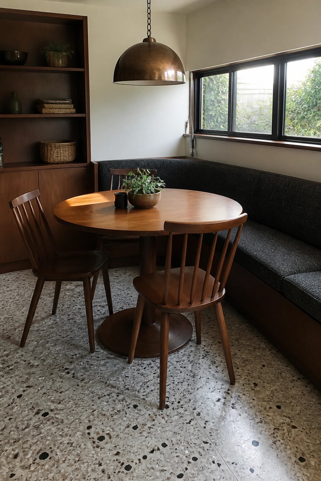 Round wooden table with spindle chairs under copper pendant in modern dining nook