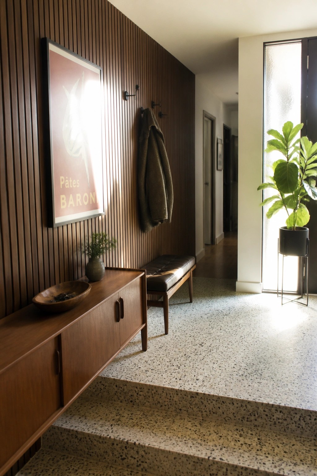 Entry hallway with vertical wood slat walls, a floating wood console, upholstered bench, and coat hooks.