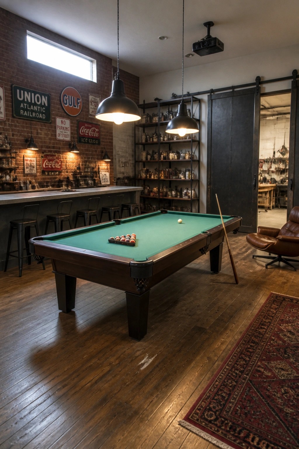 An industrial man cave with a pool table in the foreground, a long bar counter along a brick wall with stools, metal shelving units, and vintage signs on the wall.