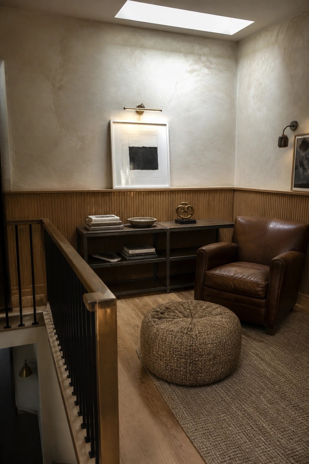 Brown leather armchair, woven ottoman, console table, and abstract art on wall.