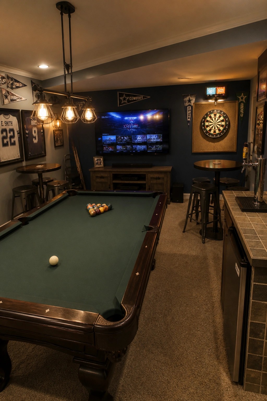 A finished basement game room with a large green pool table in the foreground, a dartboard mounted on the blue wall to the right, a television on the back wall, and sports jerseys and pennants displayed around the space.