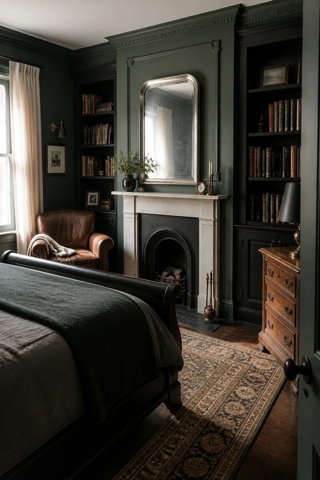 A bedroom interior with deep green walls, black built-in bookshelves flanking a white marble fireplace, a dark wooden bed, and a brown leather chair on a patterned rug.
