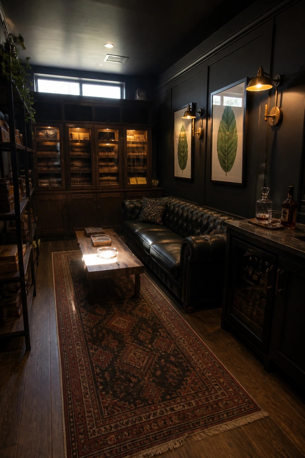 A man cave interior with matte black walls, a black leather sofa, wooden coffee table on a patterned rug, and illuminated dark wood display cabinets along the back wall.