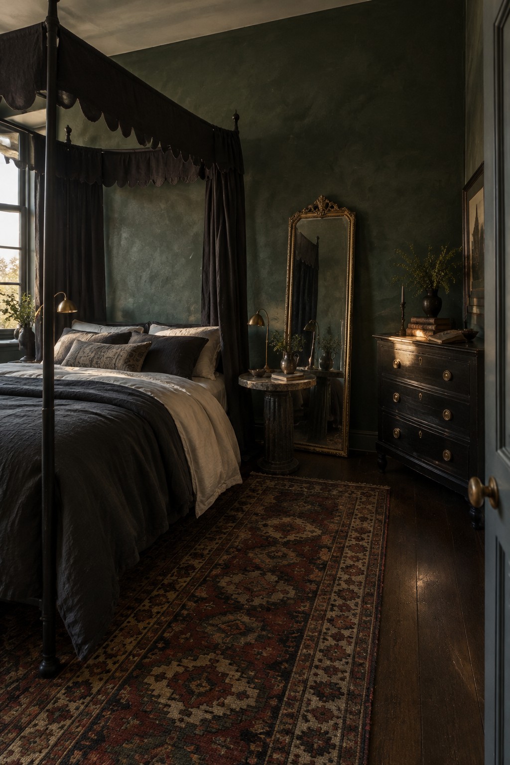 A dark four-poster canopy bed with black drapes sits against deep green walls, beside a gold-framed mirror and a dark wood chest.