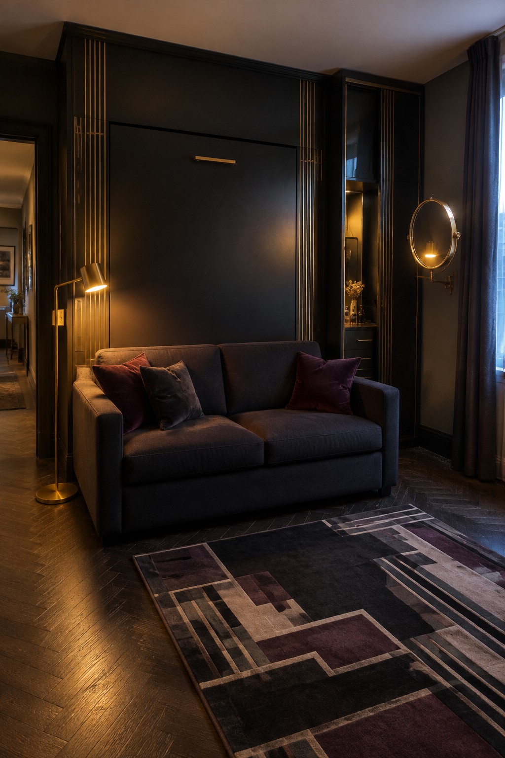A dark two-seat sofa with pillows sits against a black paneled wall beside a floor lamp and patterned rug.