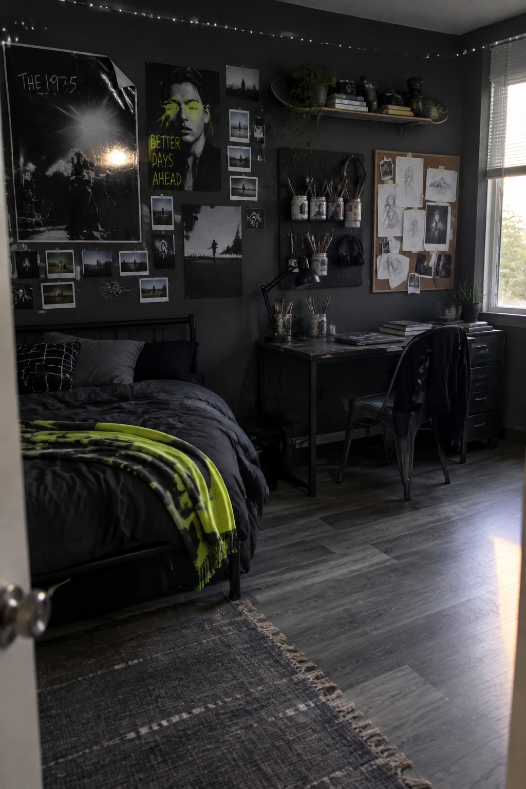 A charcoal bedroom with a bed, a desk beside a window, and posters and artwork covering the walls.