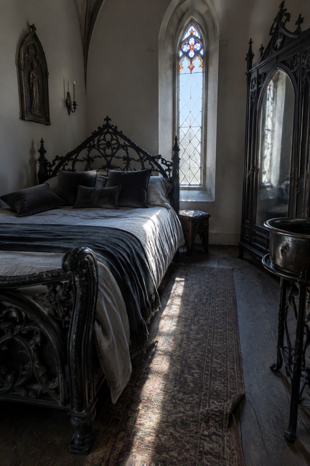 A Gothic bedroom with an ornate dark bed, a tall stained glass window, and a mirrored wardrobe.